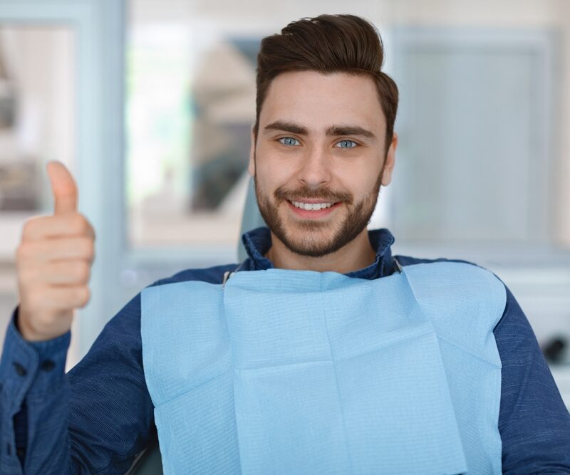 Cheerful bearded man patient sitting in dental chair - Oral and Maxillofacial Surgery